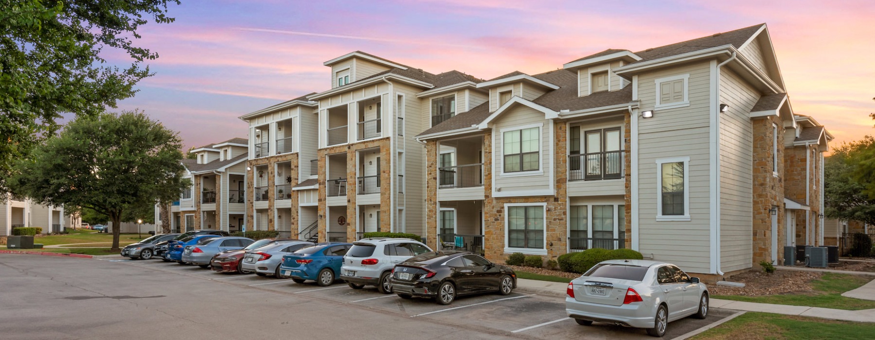 a multi-story building with windows and a parking lot with cars